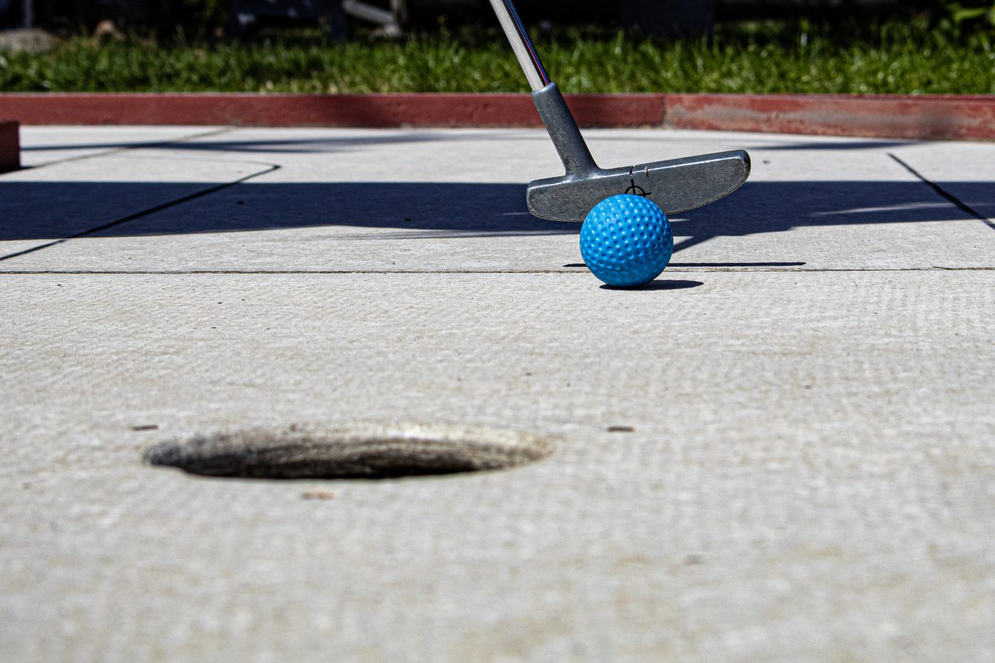 Blauer Minigolfball rollt auf das Loch zu